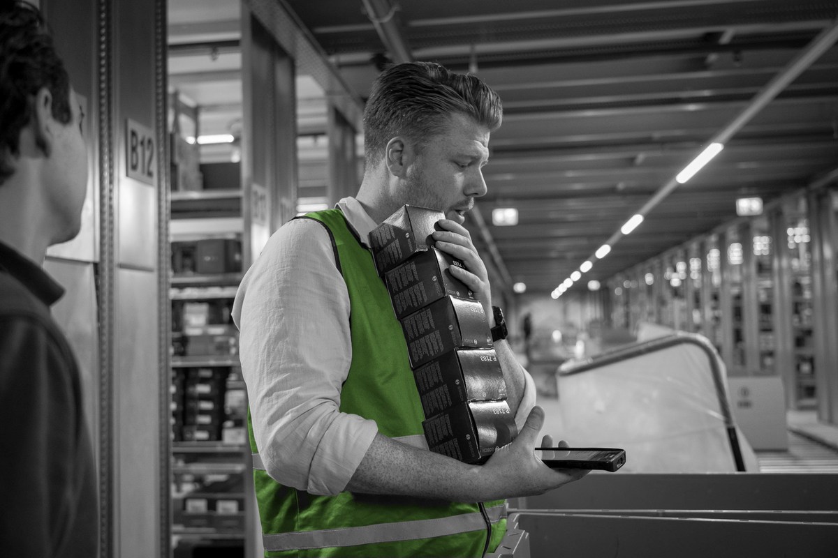 Een consultant bekijkt een onderdeel met een handterminal in het magazijn.