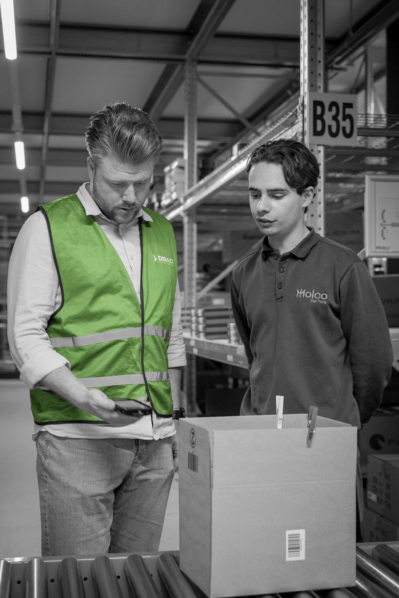 Een medewerker controleert een doos met een handterminal in het magazijn.