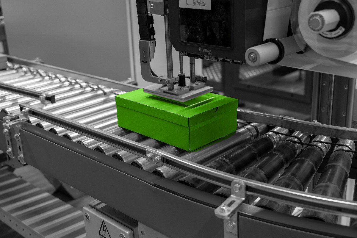 Een labelmachine brengt een verzendlabel aan op een doos.