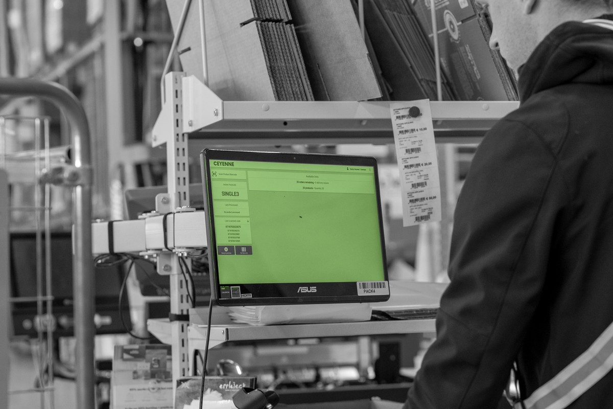 Een medewerker werkt bij een WMS-werkstation in het magazijn.