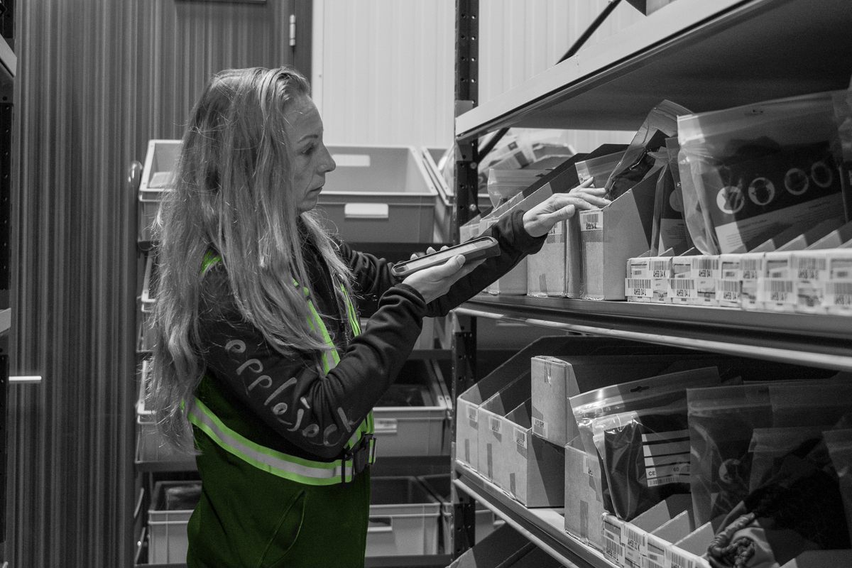 Een medewerker gebruikt een handterminal tijdens het orderpicken in het magazijn.