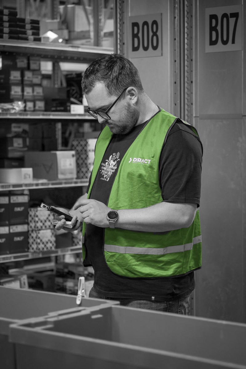 Een magazijnmedewerker verwerkt een onderdeel bij een pickbak.