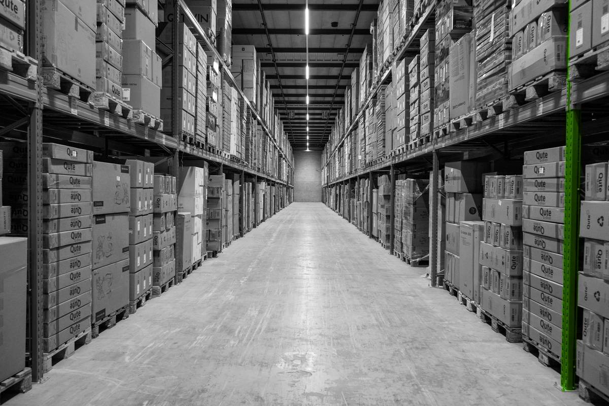 Een symmetrische magazijngang met palletstellingen en opgeslagen goederen.