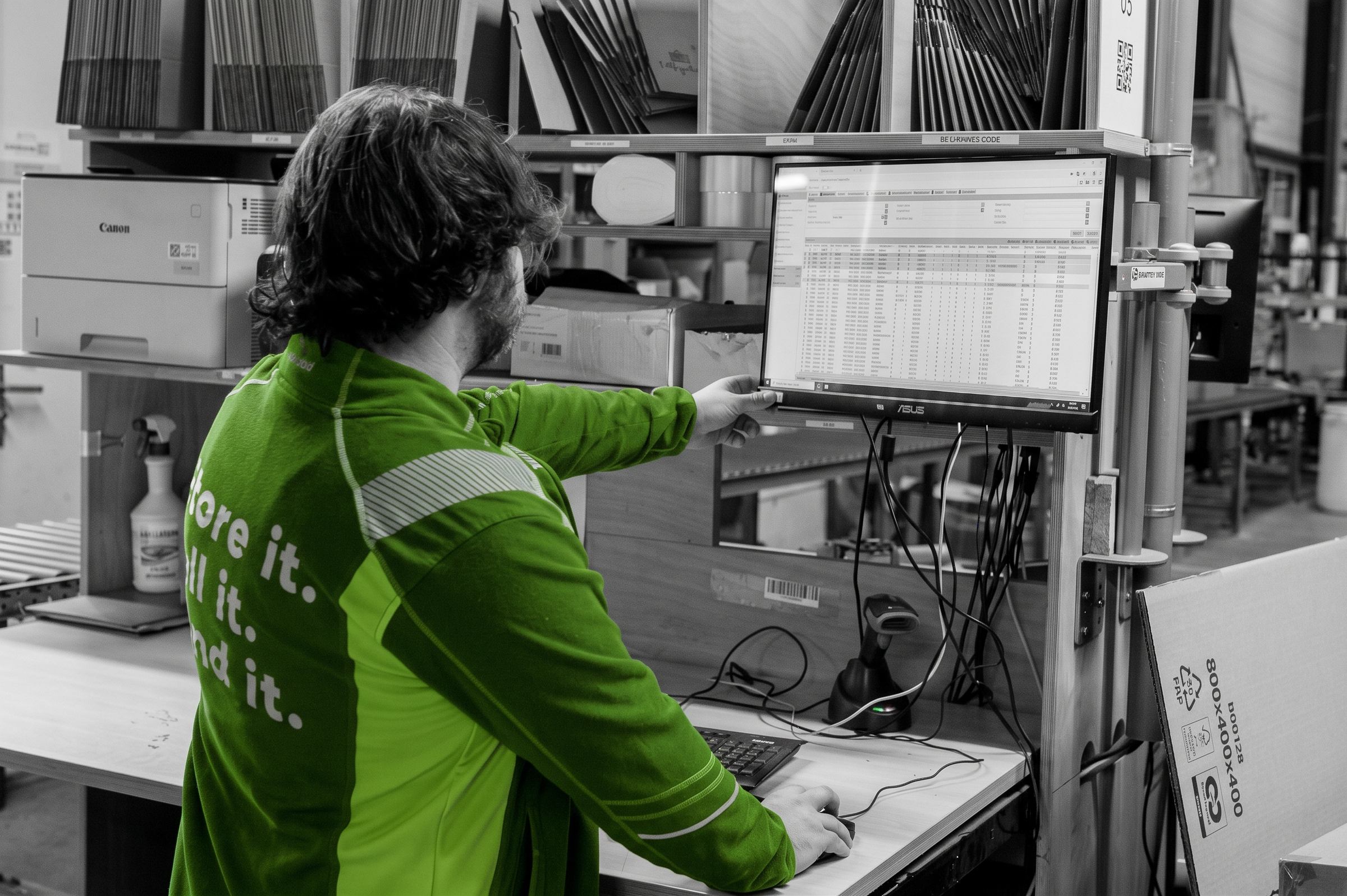 Medewerker bij een werkplek in het magazijn met het WMS-scherm voor zich